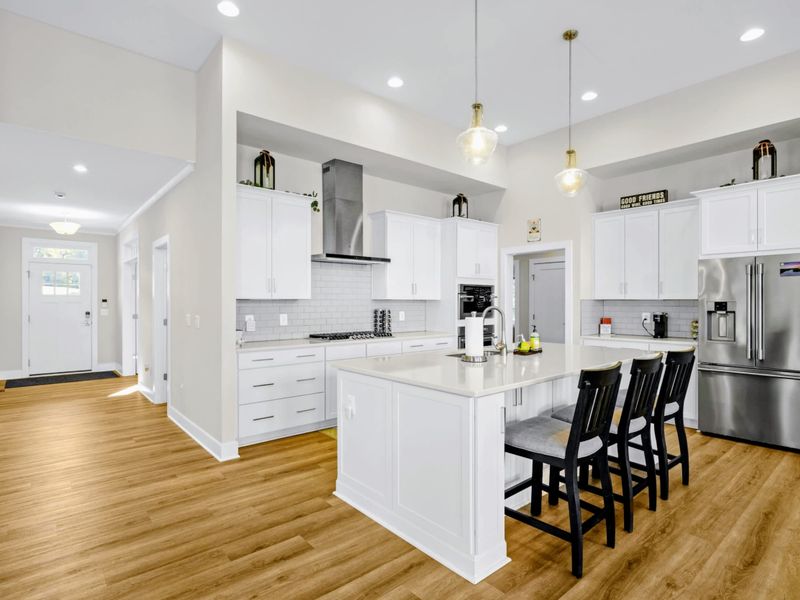Kitchen - The L-shaped island runs the length of the cook space, with gas cooktop, double ovens, and bar seating for the crew.