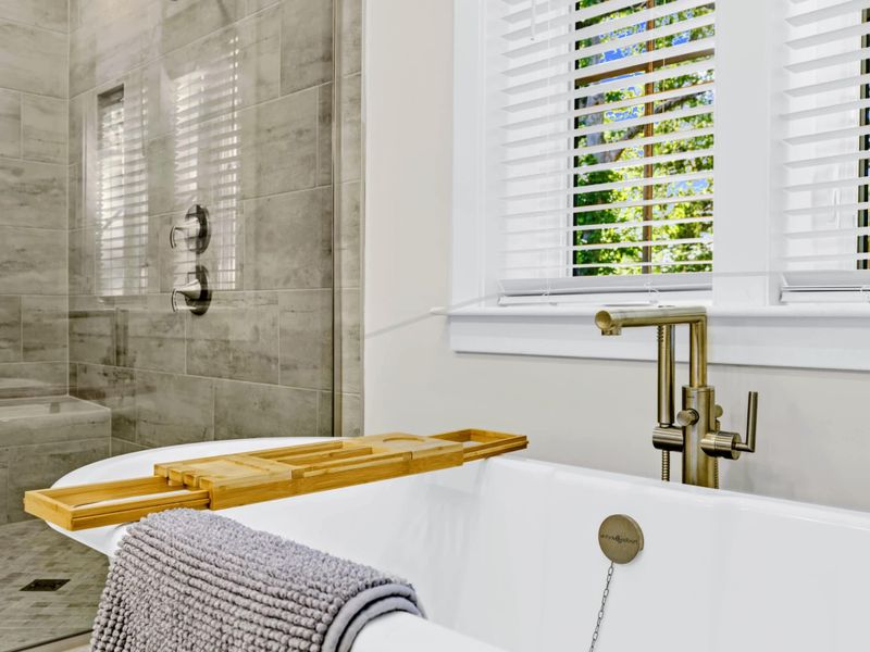 Primary Bath - Detail of the freestanding tub with brushed nickel fixtures and the tile shower with built-in seat.