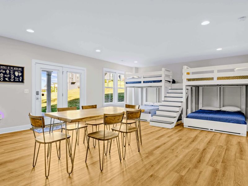 Game Room - Six-seat dining table with patio doors on one side and the custom bunk beds visible through the doorway.