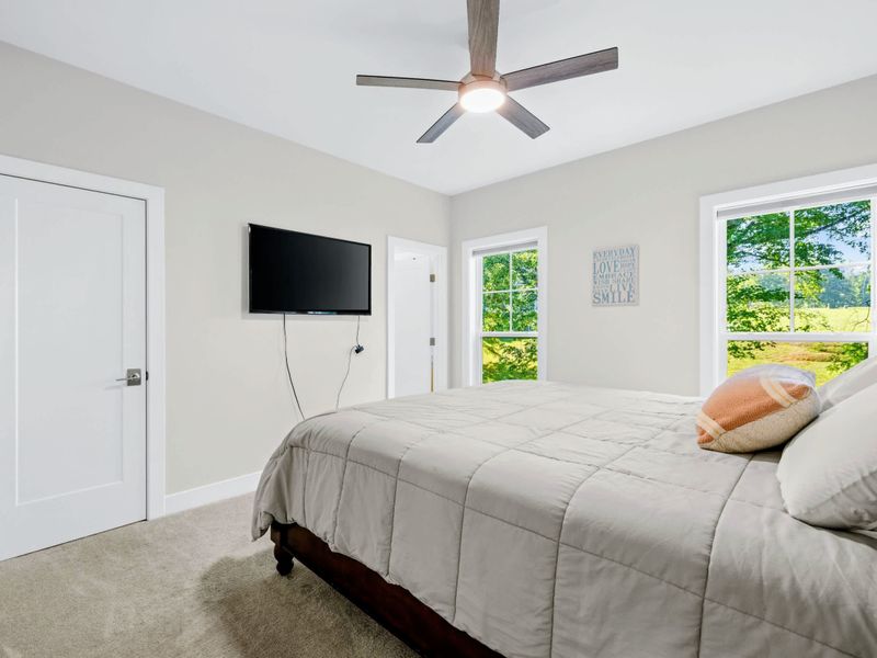 Suite 3 - Queen bed with mounted TV, bright windows over the pasture, and a warm neutral palette throughout.