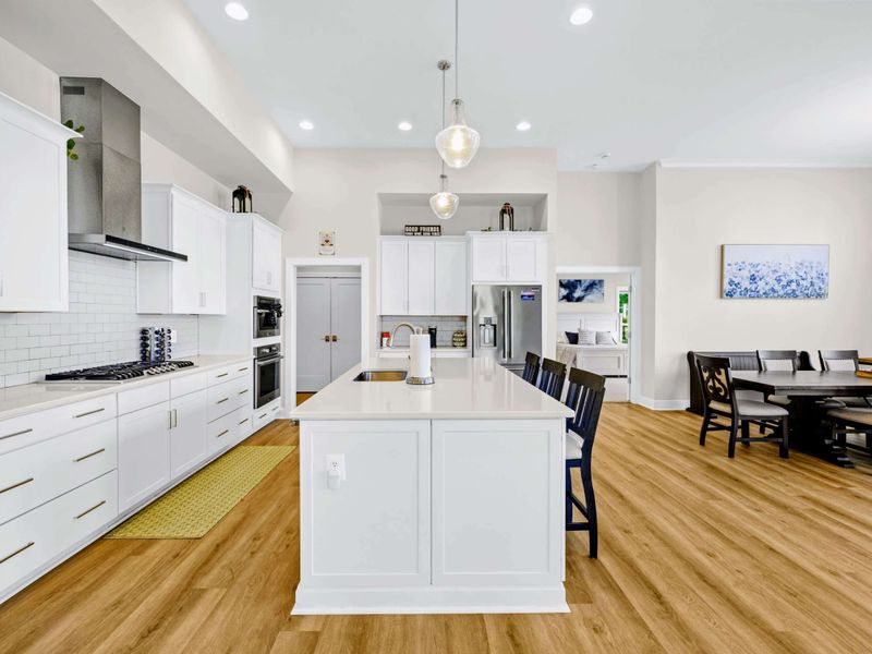 Kitchen - Long quartz island anchors the prep zone, with the dining table just steps away under matching pendant lights.
