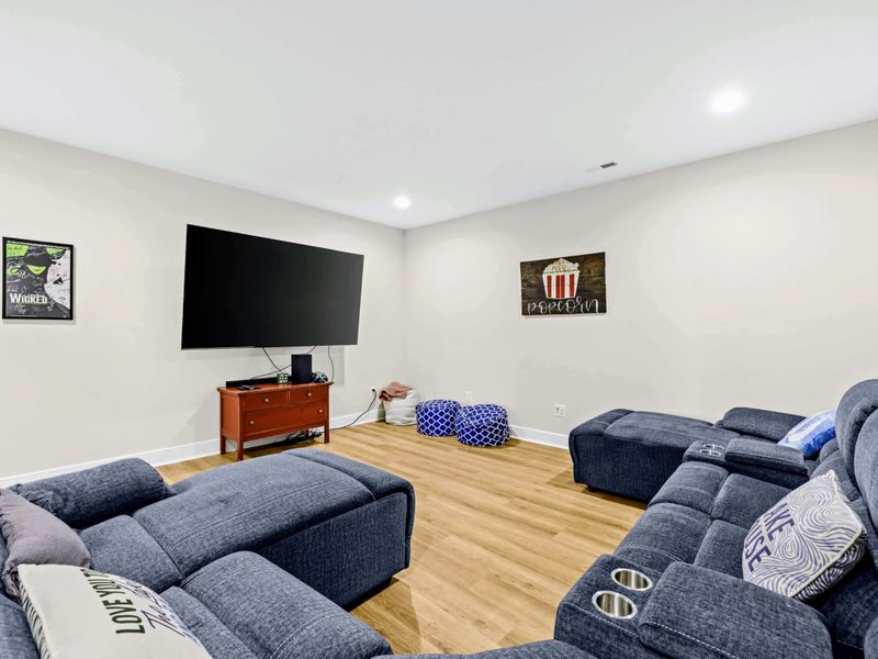 Theater - Wide angle of the big screen, sectional sofa, and accent posters that set the popcorn-and-cinema mood.