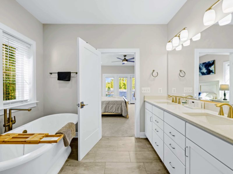 Primary Bath - Freestanding soaking tub with a wood caddy and double vanity, the doorway opening into the primary suite.
