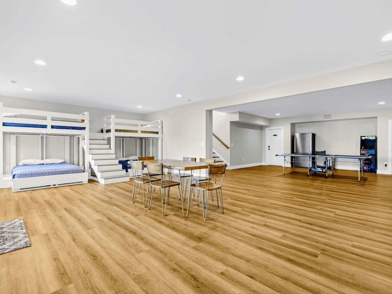 Game Room - Wide view ties the bunk wall, dining table, ping pong, and arcade together in one open lake-level zone.