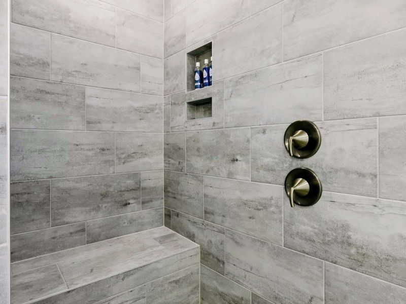 Primary Bath - Walk-in tile shower with built-in seat, niche, and dual rainfall and wall-mounted heads for two.