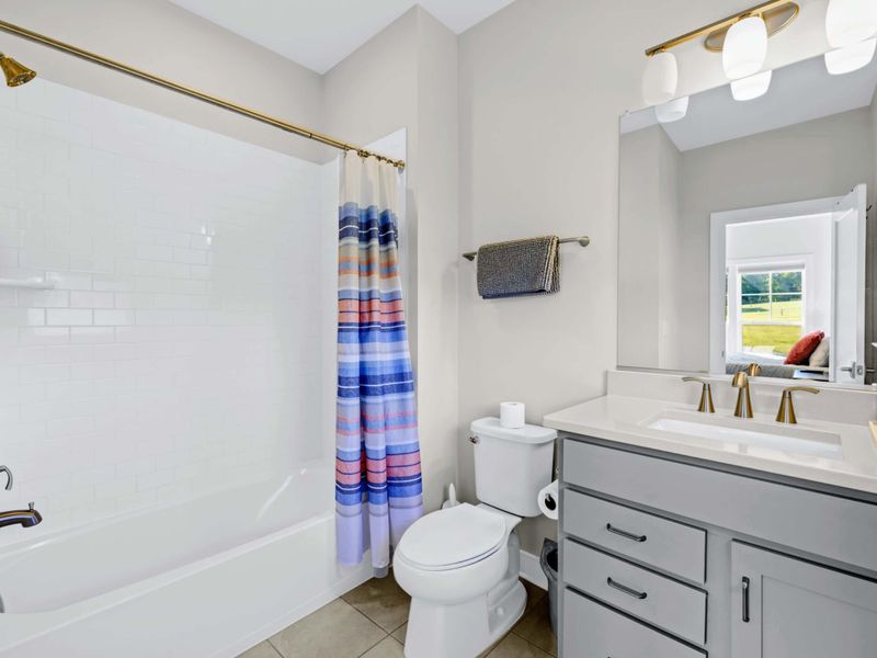 Suite 2 Bath - Subway tile tub-shower combo with brushed gold fixtures, single vanity, and bright window light.