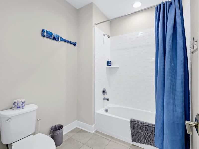 Suite 4 Bath - Subway tile tub-shower combo with a playful blue oar accent on the wall and a waffle towel ready to go.