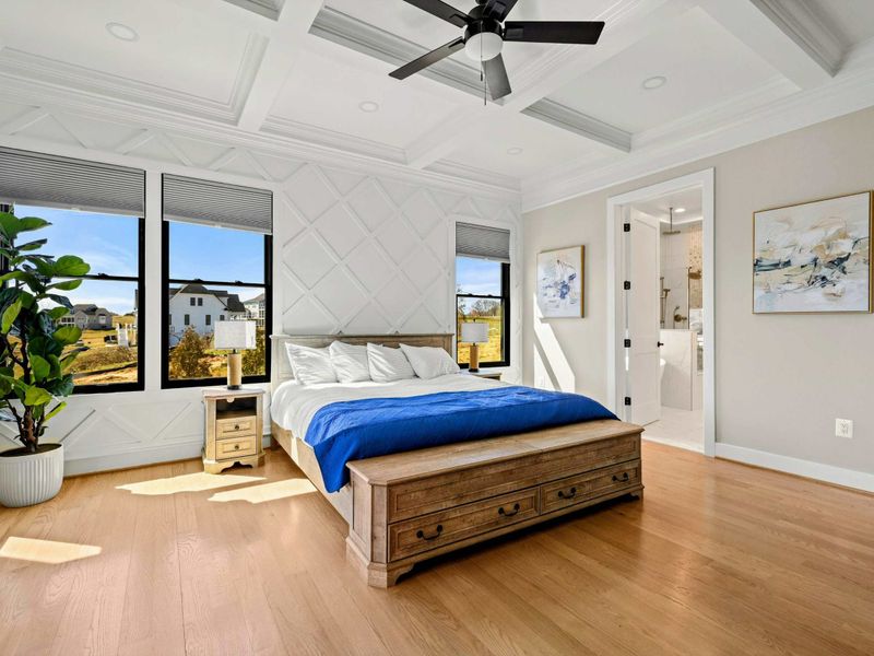 Primary Suite: Elegant and tranquil retreat featuring a custom accent wall, coffered ceiling, luxurious king bed, and an en-suite spa-like bathroom for ultimate relaxation.