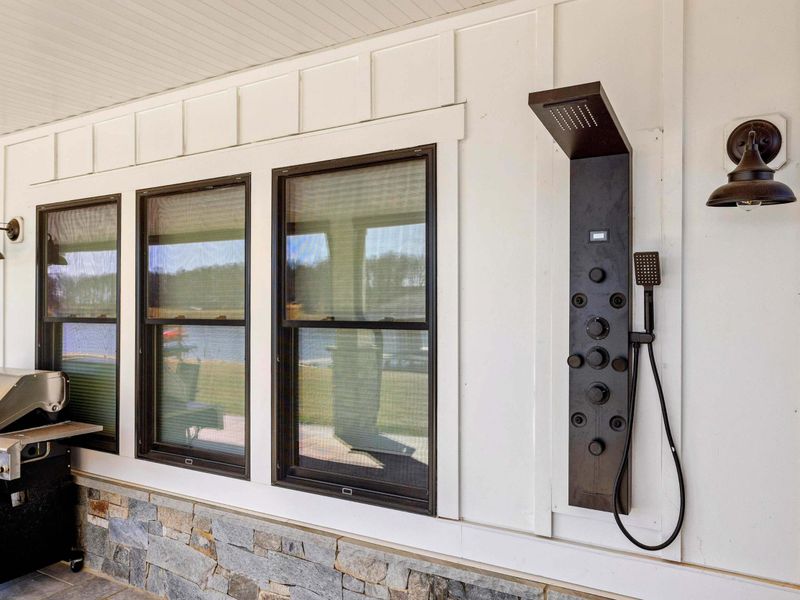 Outdoor Shower & Grill: Convenient outdoor shower with multiple jets for rinsing off after a swim, paired with a stainless steel propane BBQ grill, perfect for lakeside cookouts and easy cleanup.