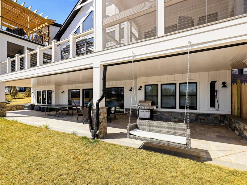 Lakeside Patio: Relax in this inviting outdoor space featuring a cozy hanging bench, dining area, grill station, and seamless access to the backyard, perfect for entertaining and unwinding by the lake.