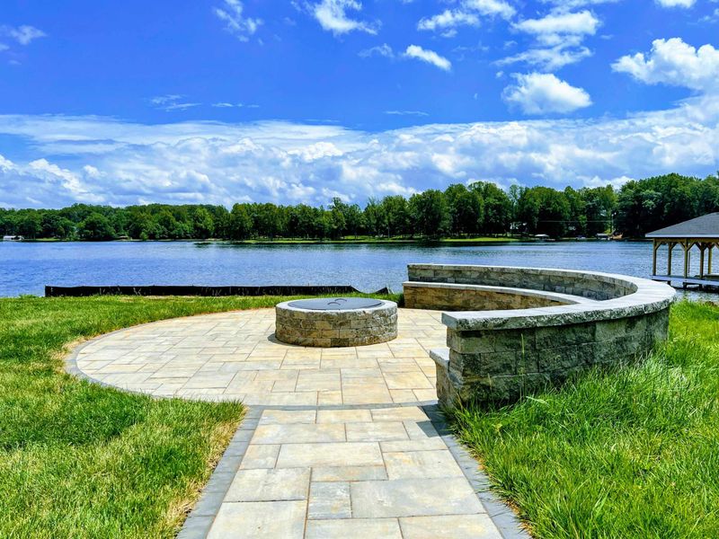 Fire Pit - Stone fire pit with curved bench seating on a paver patio overlooking the lake and covered dock.