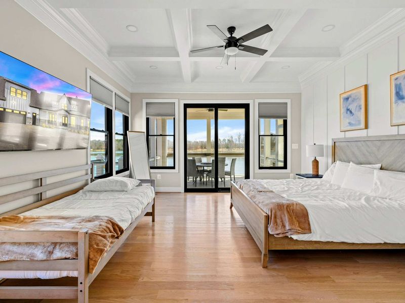 Suite #2: Beautifully designed bedroom featuring a king bed, additional twin bed, coffered ceiling, a mounted TV, and private patio access with breathtaking lake views.