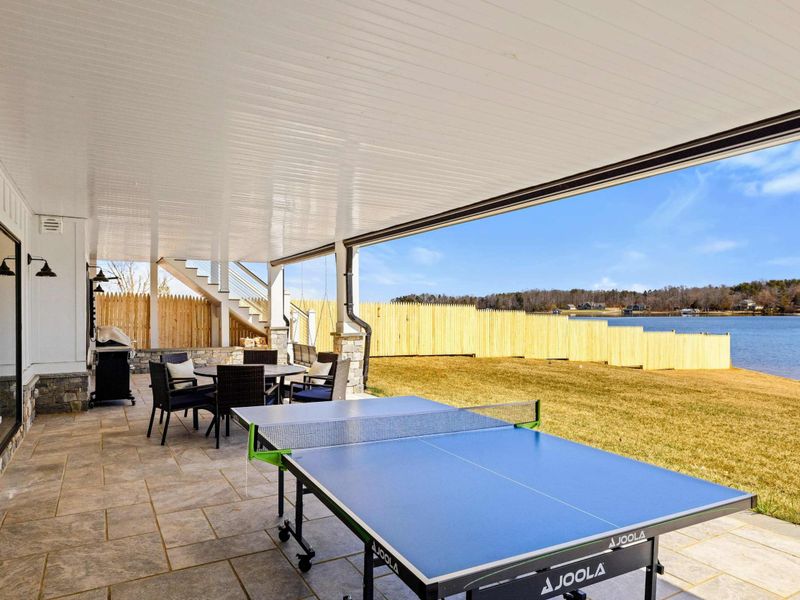 Lakeside Patio Entertainment: Spacious covered patio featuring a ping pong table, outdoor dining area, and breathtaking lake views—perfect for games, meals, and relaxation by the water.