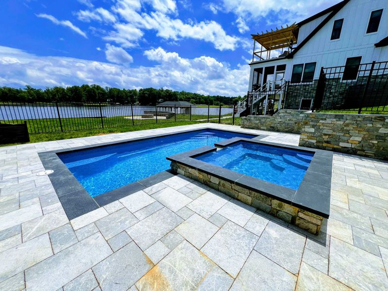 Pool and Spa - Wide view with the home's upper balcony and rooftop deck framing the pool area against a big Virginia sky.