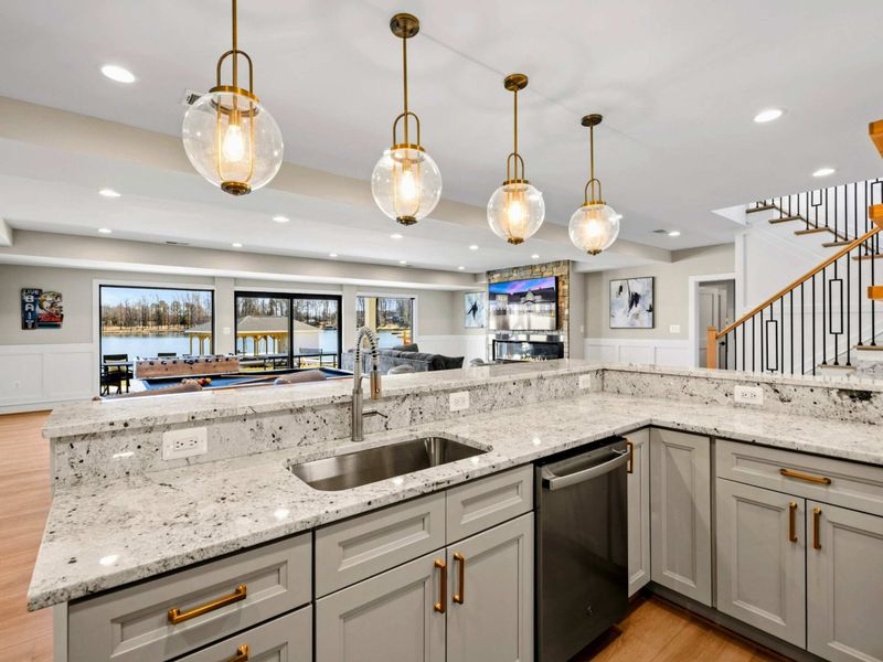 Entertainer’s Bar & Kitchenette: Elegant and functional space featuring granite countertops, stylish pendant lighting, and a seamless flow to the game room and lounge, offering stunning lake views.