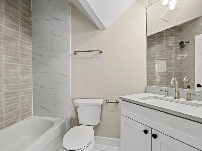 Suite #3 Bathroom: Modern en-suite bathroom featuring a sleek quartz vanity, stylish lighting, and a tub-shower combo with elegant tile accents for a relaxing and refreshing experience.