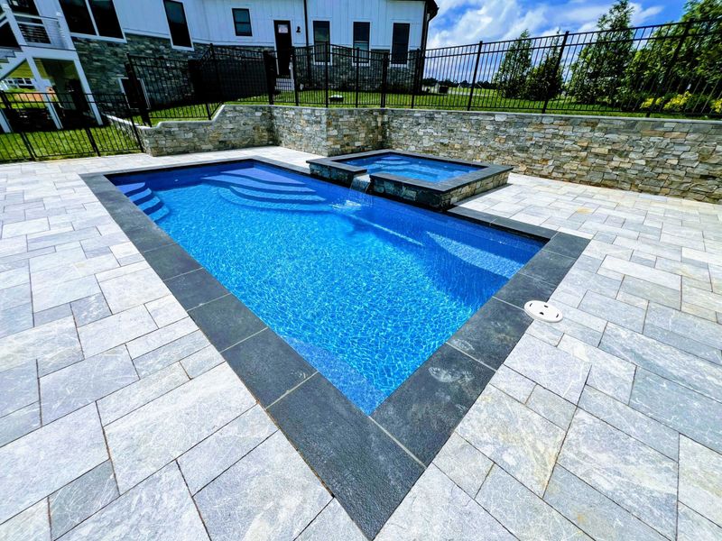 Pool and Spa - Corner angle of the pool and raised spa with natural stone coping and bluestone paver deck.