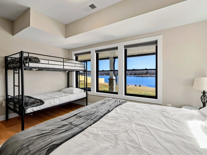 Suite #7: Spacious room with a king bed and a twin-over-twin bunk bed. Large windows offer stunning lake views, filling the room with natural light.
