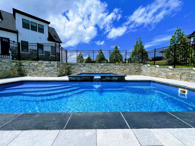 Pool - View from the shallow end showing the built-in steps, stone water features, and iron safety fencing.