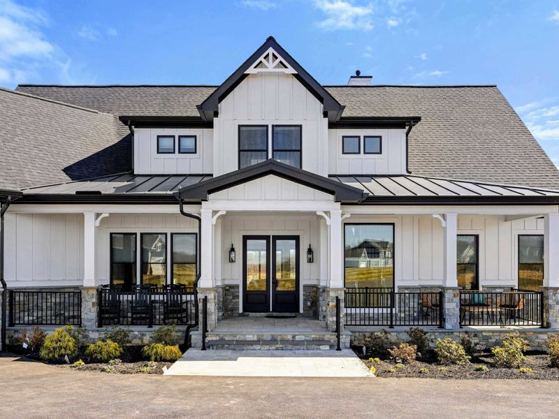 Front Exterior: A stunning modern farmhouse design featuring board and batten siding, stone accents, and a welcoming covered porch with black metal railings.