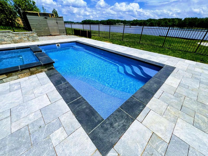 Pool - Clean lines of the pool and spa on the bluestone paver patio with lake views and iron fencing.