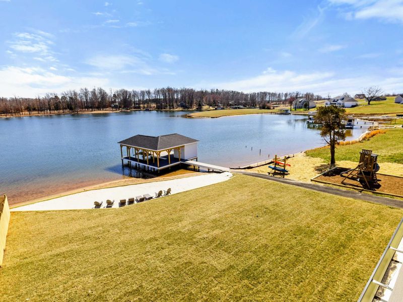 Scenic Lakefront View: Breathtaking panoramic view of Lake Anna featuring a private sandy beach, boat dock, fire pit seating area, and a playground—perfect for relaxation and outdoor fun.