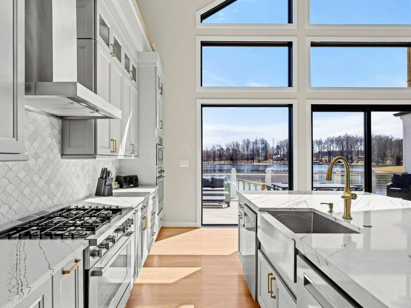 Chef’s Kitchen with a View: Elegant and functional kitchen featuring high-end appliances, quartz countertops, a stylish backsplash, and breathtaking lake views through soaring floor-to-ceiling windows.
