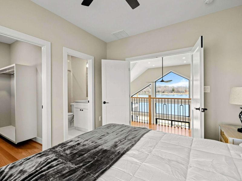 Suite #6: Features a king-sized bed, private en-suite bathroom, and a walk-in closet. Double doors open to a balcony overlooking the great room and offering scenic lake views. A stylish and comfortable retreat.