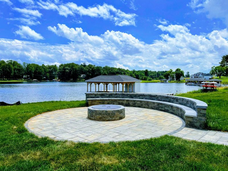 Fire Pit - Alternate angle of the lakefront fire pit with curved stone seating, gazebo dock, and open water views.