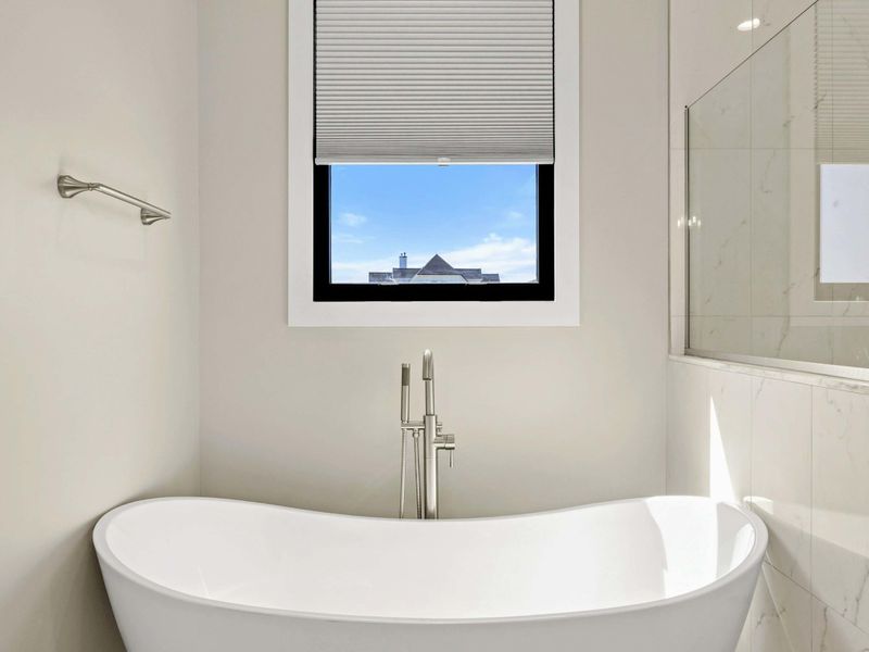 Freestanding Soaking Tub: A serene escape featuring a modern freestanding tub, elegant fixtures, and a peaceful window view—perfect for unwinding in luxury.