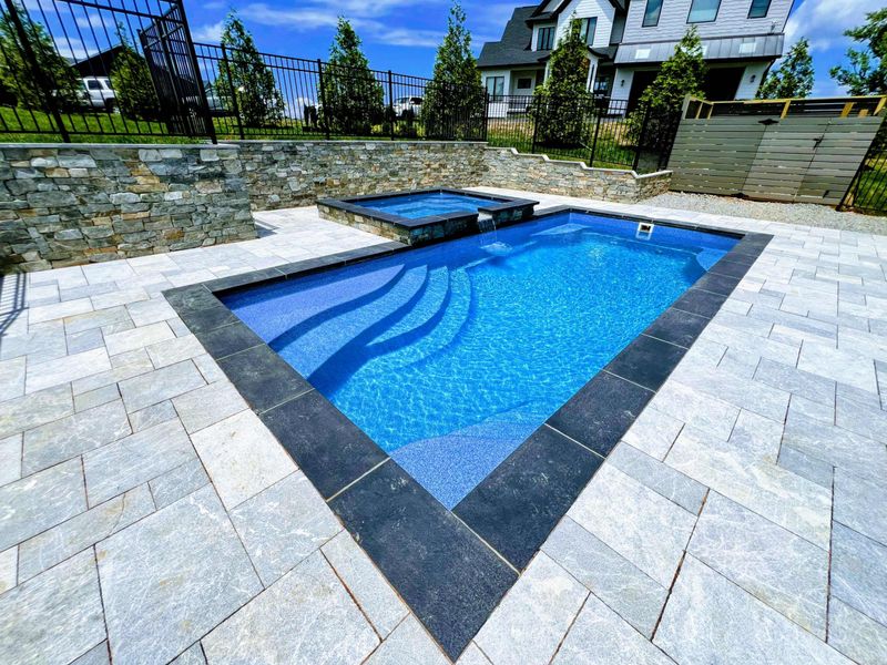 Pool - Crystal-clear pool with stone retaining wall, built-in steps, and the home's upper deck visible above.