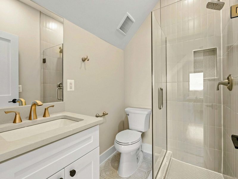 Suite #5 Bathroom: Features a walk-in shower with sleek glass doors, a modern vanity with gold fixtures, and stylish tile flooring. Designed for comfort and convenience.