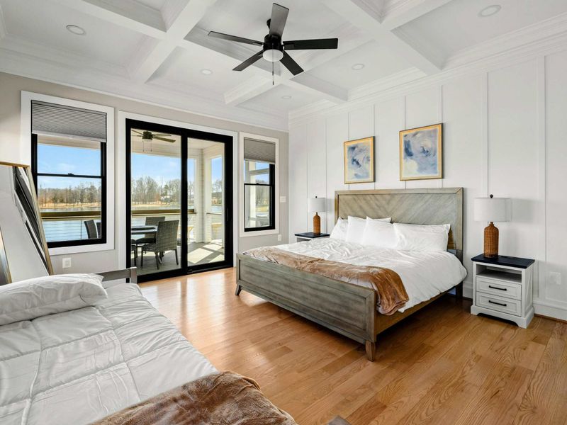 Suite #2: Spacious and elegantly designed bedroom featuring a king bed, additional twin bed, coffered ceiling, private patio access, and serene lake views for a restful retreat.