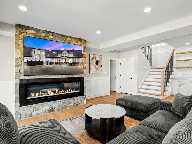 Game Room Lounge: Cozy and stylish lounge area featuring a plush sectional, a sleek stone fireplace, and a large TV, creating the perfect spot for movie nights and relaxation.