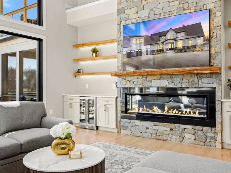 Great Room Fireplace: Striking floor-to-ceiling stone fireplace with a modern linear gas insert, built-in shelving, and a wet bar, creating the perfect ambiance for cozy gatherings and relaxation.