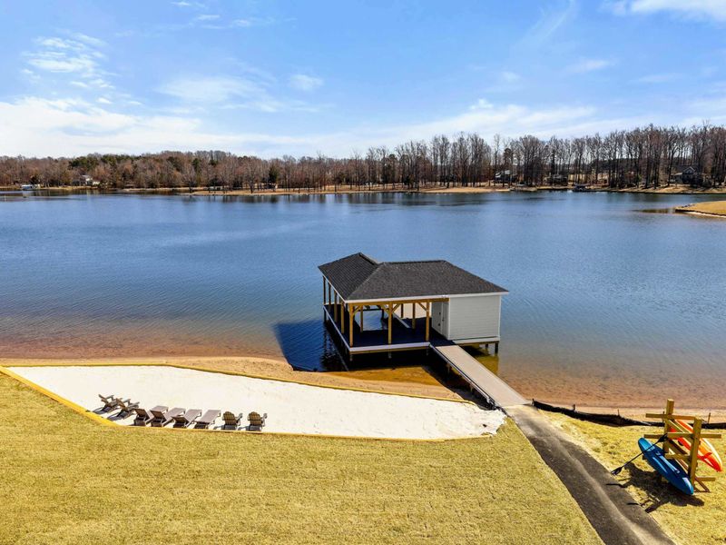 View from Suite #4 Private Balcony: A breathtaking perspective overlooking the serene lake, private sandy beach, and boat dock. This stunning view offers the perfect backdrop for relaxation, capturing the peaceful essence of lakefront living.