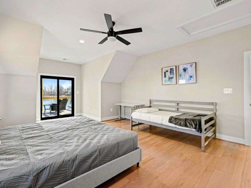 Suite #3: Spacious and inviting bedroom featuring a king bed, an additional twin bed, private balcony access, and stunning lake views for a peaceful and comfortable retreat.
