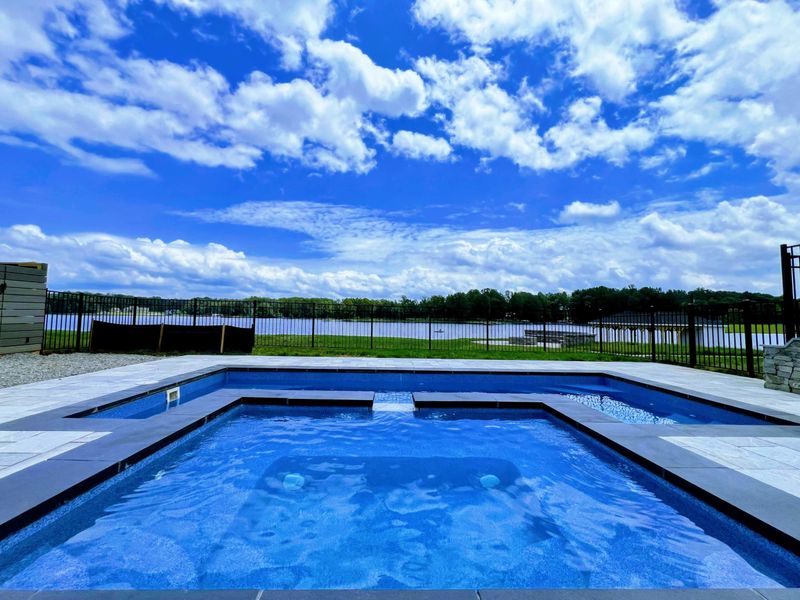 Pool - Infinity-edge view from the pool looking out over the iron fence toward the lake on a sunny day.