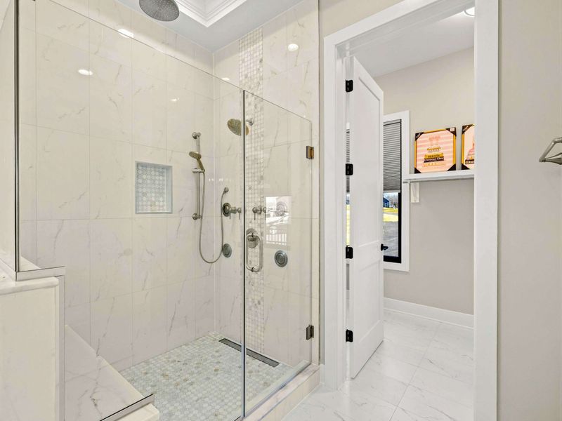 Spa-Inspired Walk-In Shower: Elegant glass-enclosed shower featuring marble tile, rainfall and handheld showerheads, multiple body jets, and a built-in bench for a luxurious bathing experience.