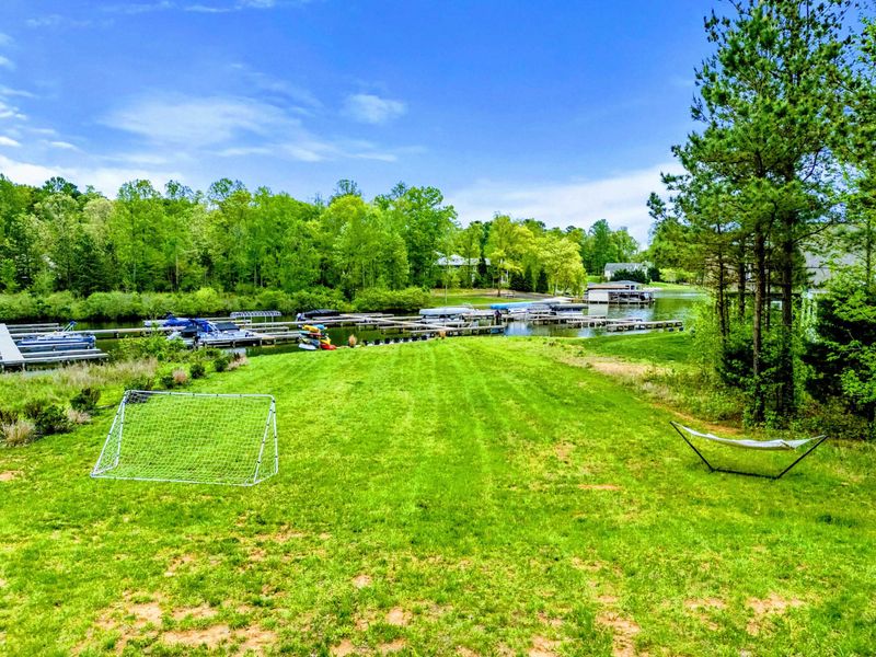 Backyard Play - A soccer goal on the open lawn and a shaded hammock strung by the trees, with the community marina just across the cove.