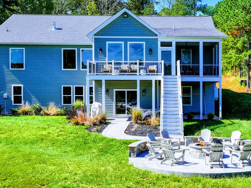 Lake-Facing Exterior - The home opens fully to the water, screened porch and balcony stacked above the walkout level, with the fire pit patio just off the lawn.