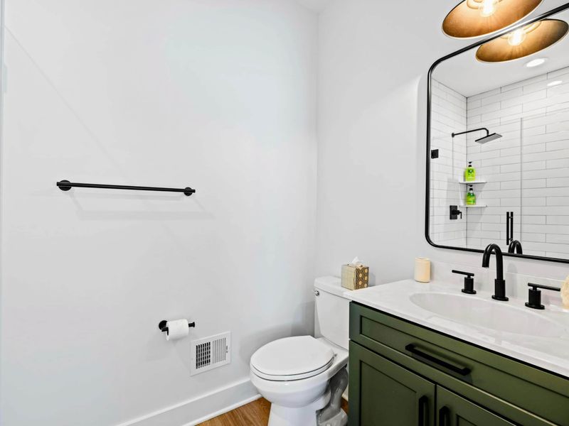 Ensuite Bath - A green vanity with matte-black fixtures and a walk-in shower serves the main-level king suite in style.