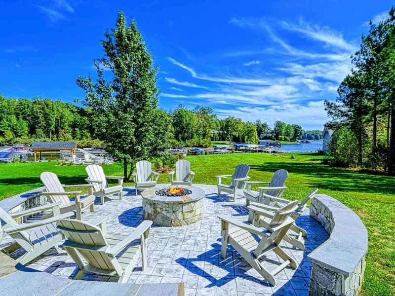 Fire Pit Nights - Cream Adirondack chairs circle the gas fire pit on a stamped-stone patio, the marina and lake glinting just beyond the lawn.