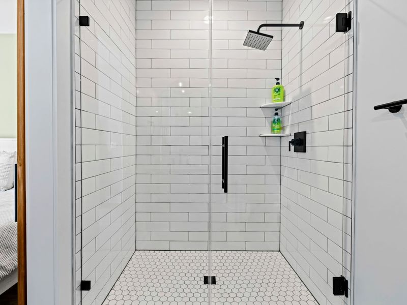 Walk-In Shower - Classic white subway tile and a black rainhead keep this guest ensuite crisp, bright, and easy.