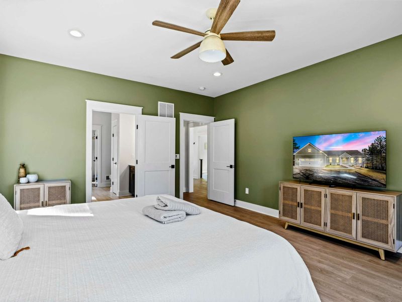 Primary Suite - Bright and serene with a king bed, ceiling fan, and Smart TV, plus a private ensuite through the double doors.