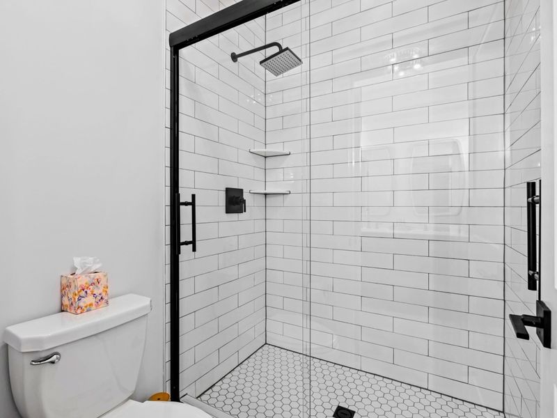 Walk-In Shower - White subway tile and matte-black fixtures keep the shared Jack-and-Jill bath crisp and simple to share.