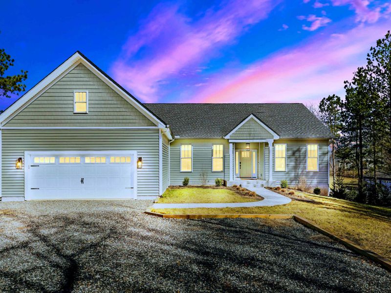 Welcome Home - The home glows at dusk above a gravel drive and two-car garage, your private Lake Anna retreat in The Waters.