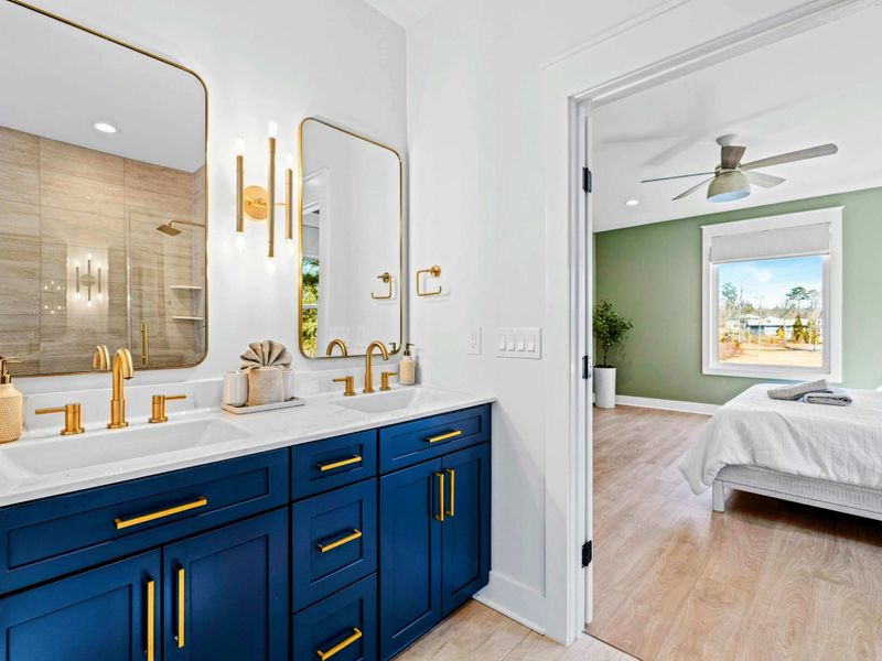 Primary Bath - A navy double vanity with brushed-gold fixtures and a glass walk-in shower bring a spa feel to the main-level suite.