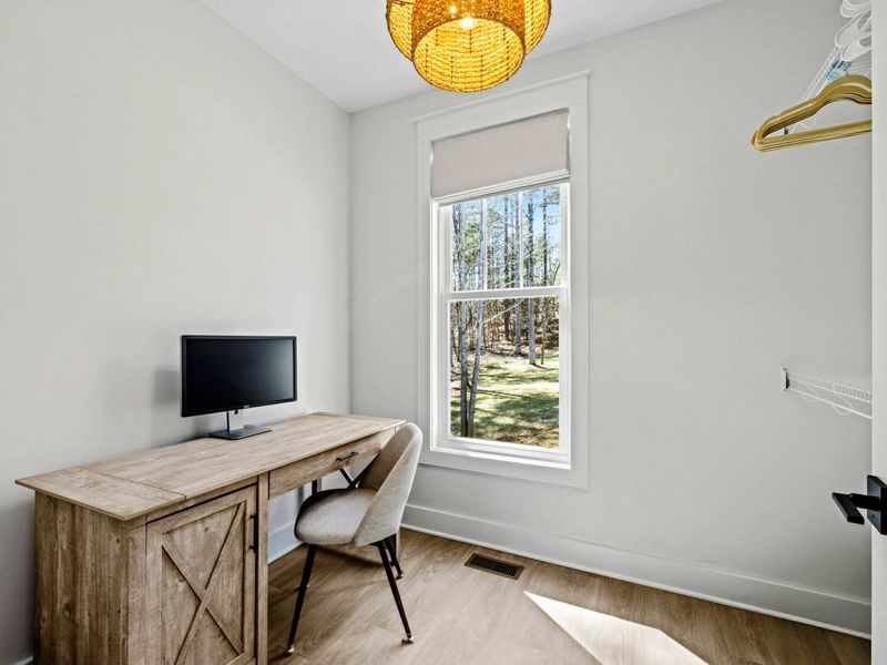 Work Nook - A tucked-away desk with a monitor and treetop view makes remote work easy without leaving the primary suite.