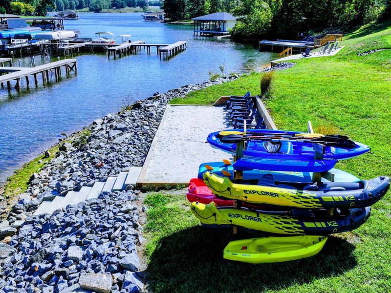 Beach & Launch - A concrete water-entry pad and stone steps lead into the cove, kayaks racked steps away and the marina just down the shore.